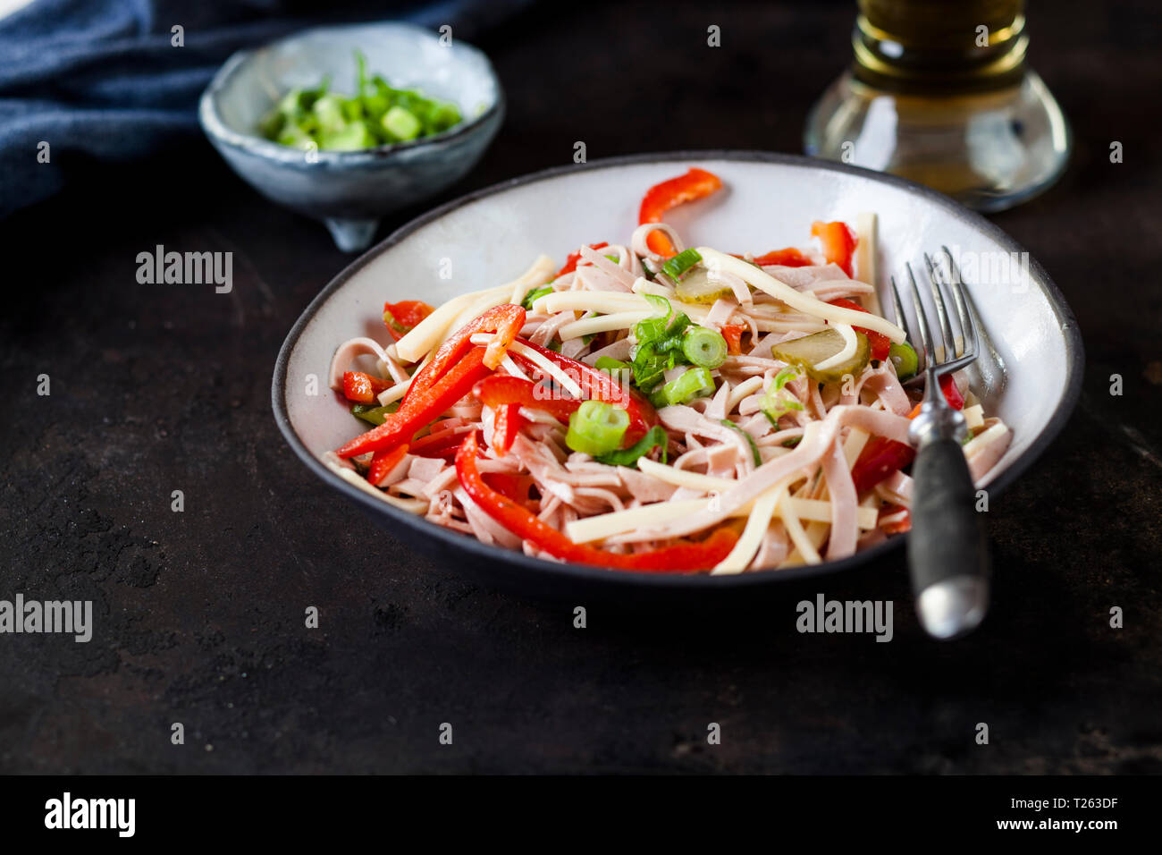 Sausage salad with cheese, red bell pepper, spring onions and gherkins Stock Photo