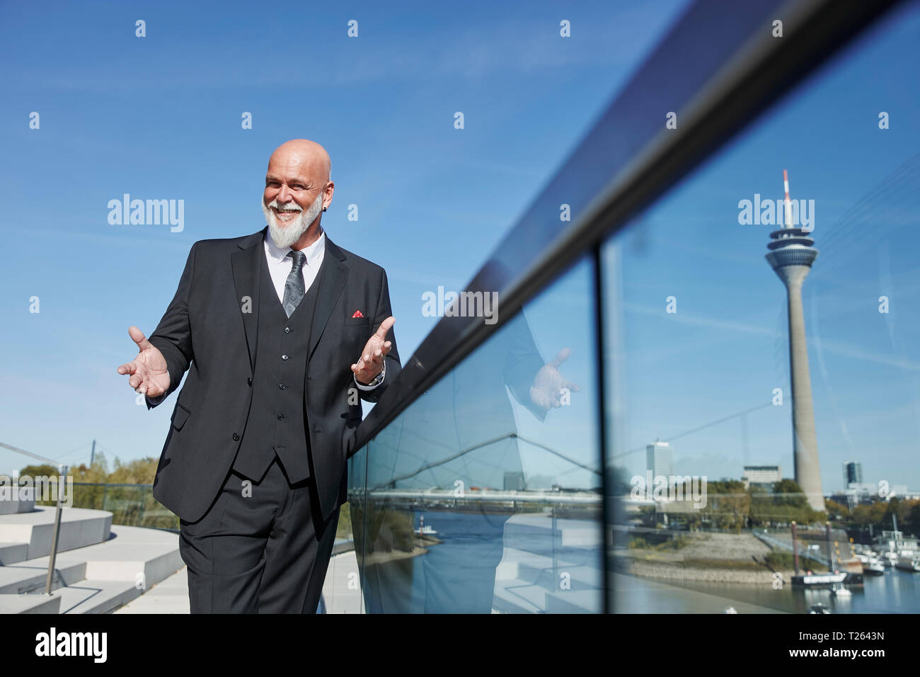 Elegant businessman standing on a bridge, making inviting gesture Stock Photo