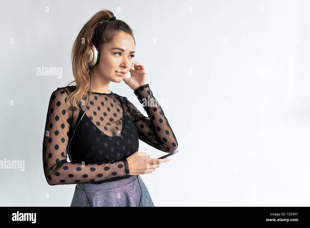 Young, elegant woman, wearing headphones, using smartphone Stock Photo
