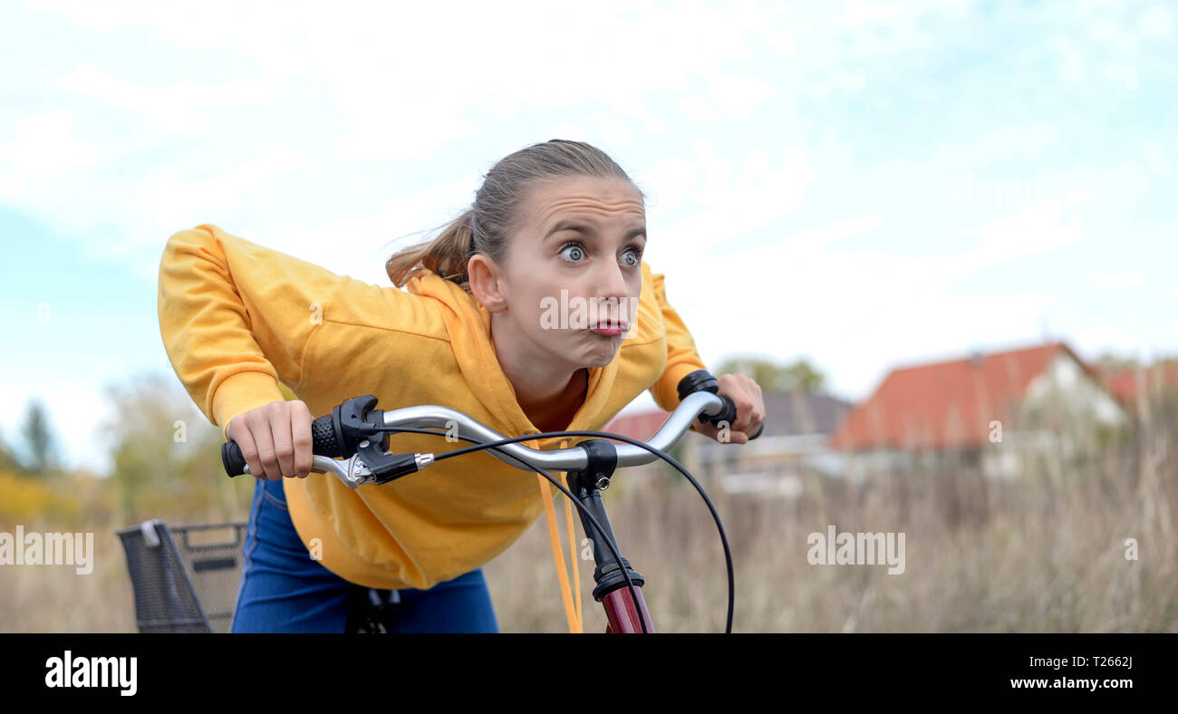 Portrat of girl with bicycle wearing yellow hooded jacket Stock Photo