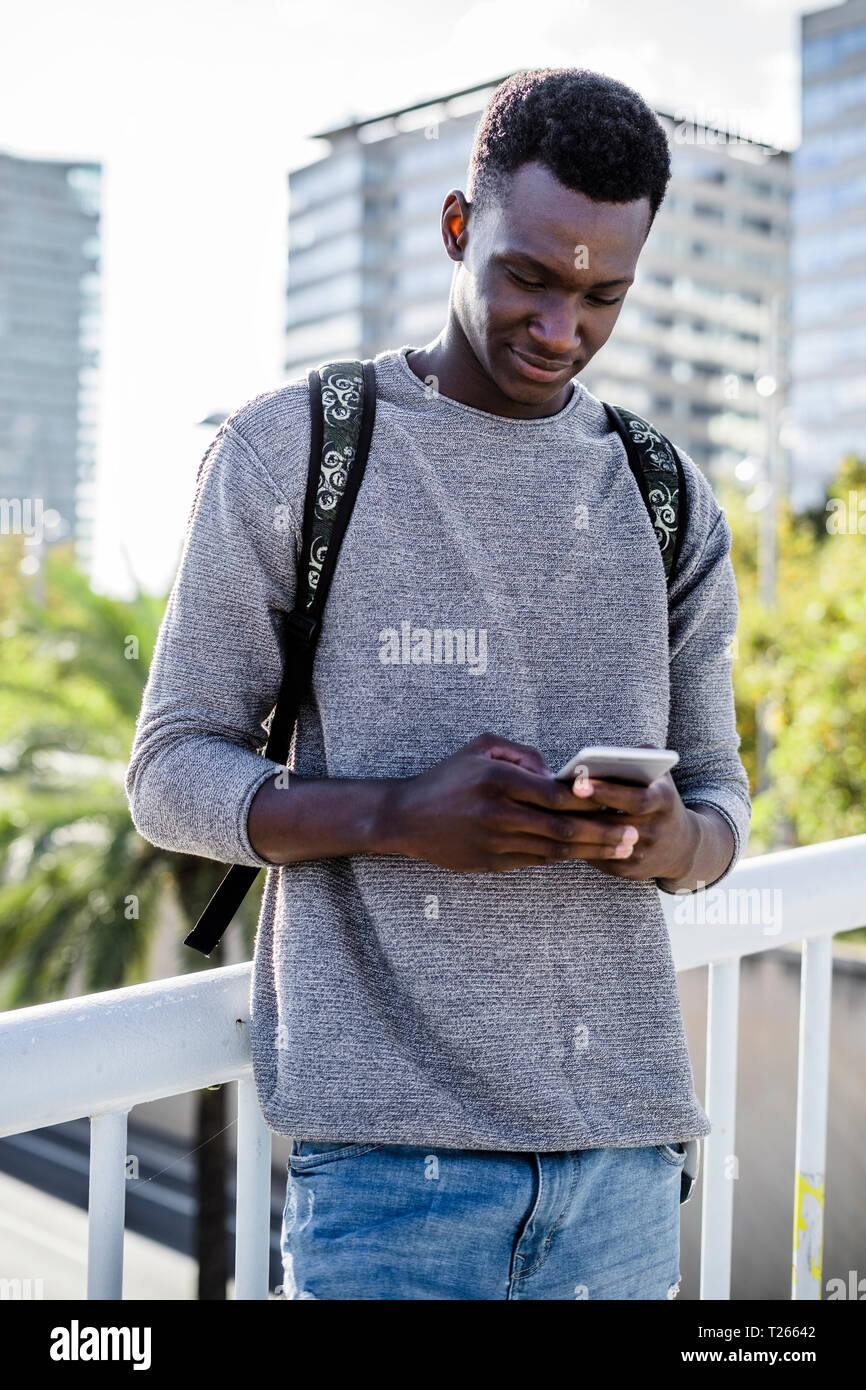Young man standing on a bridge, using smartphone Stock Photo