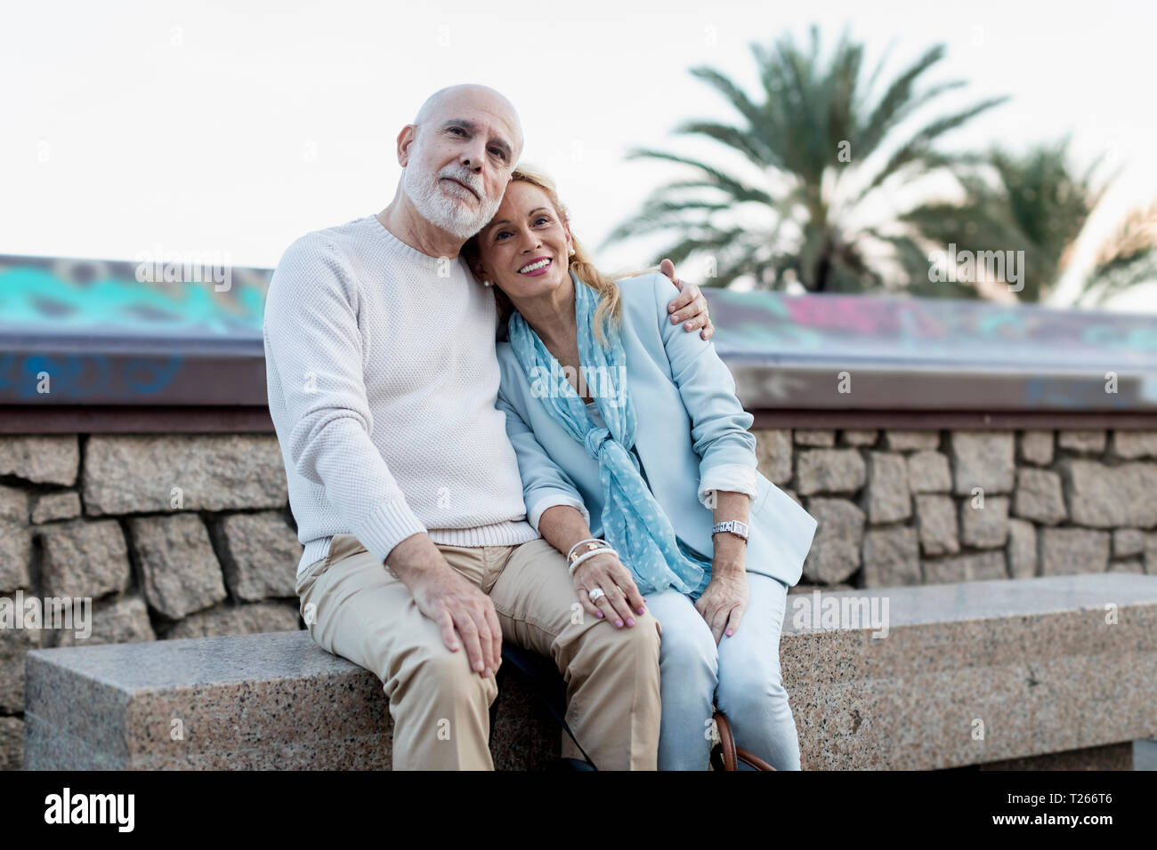 Spain, Barcelona, happy senior couple embracing on a bench Stock Photo