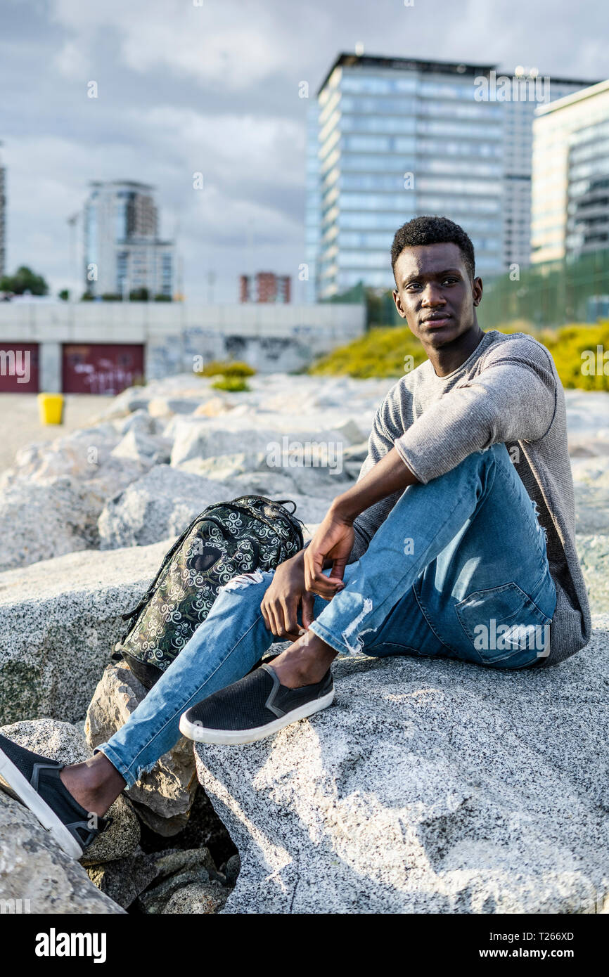 Young man sitting on the rocks hi-res stock photography and images - Alamy