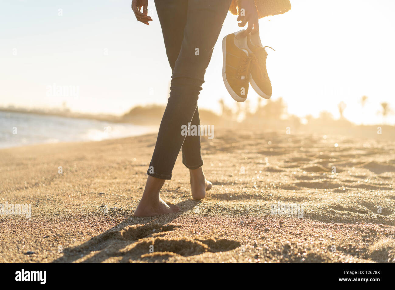 Barefoot woman on the beach carrying her shoes Stock Photo Alamy