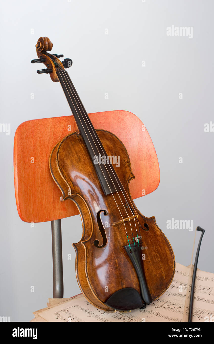 Violin, bow and sheet music on wooden chair, close-up Stock Photo