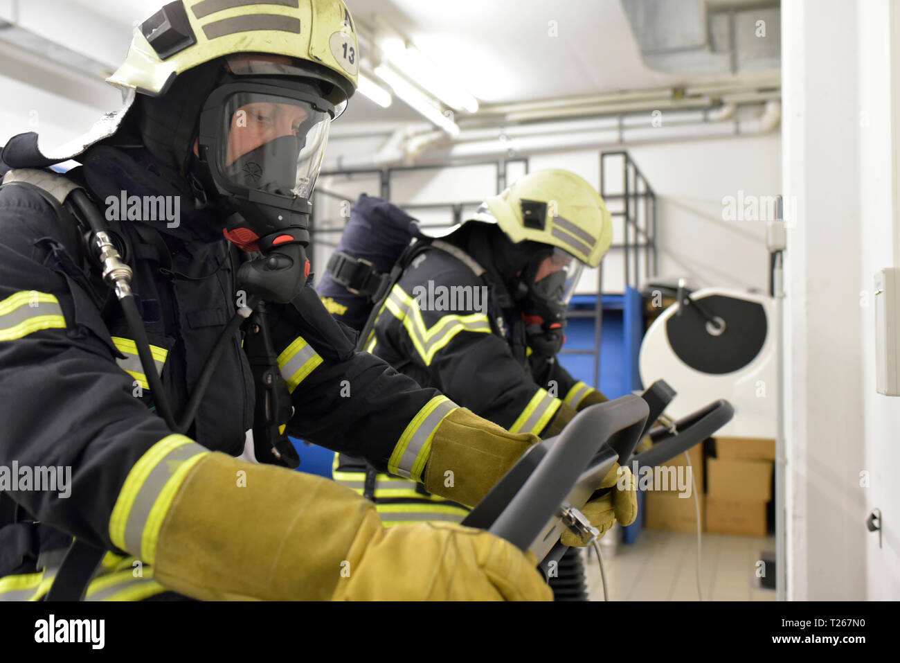 Two firefighters with respirator and air tank exercising on treadmill Stock Photo