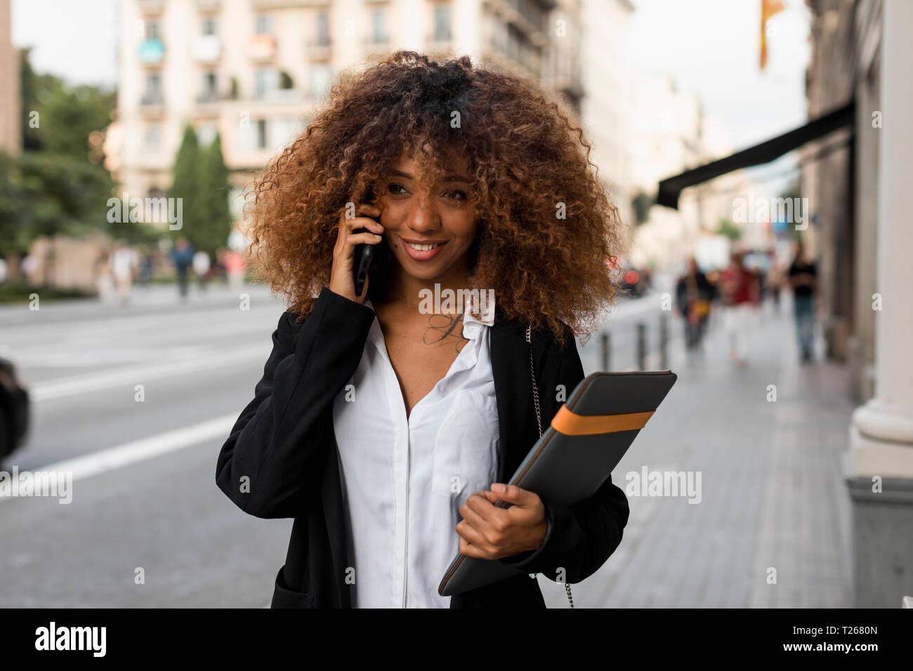 Young woman using smartphone, laptop bag Stock Photo