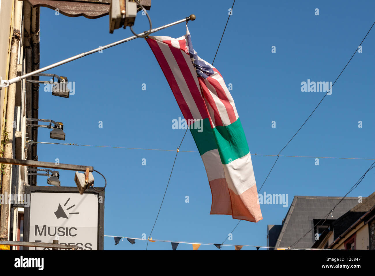 Irish tricolor made-up enhanced mixed fabricated fictional hanging Irish American flag waving outside restaurant in Killarney, County Kerry, Ireland Stock Photo
