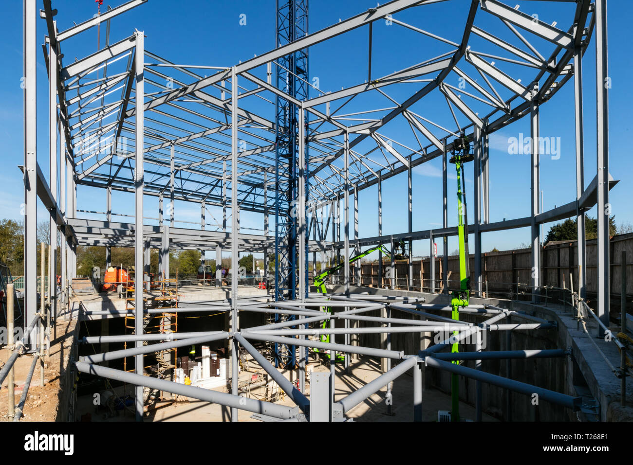 Steel frame of new building in construction set against bright blue sky ...