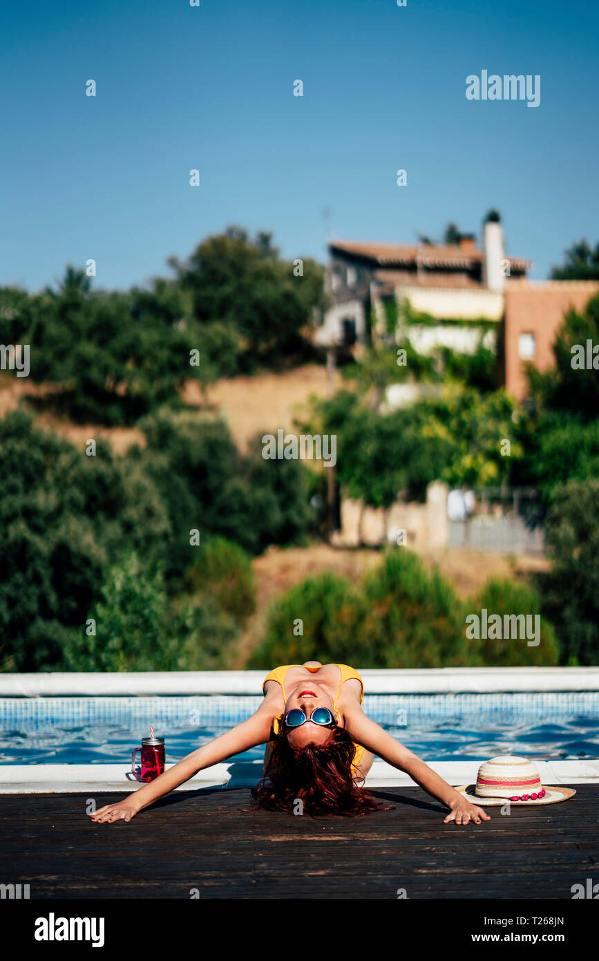 Pretty woman in a swimsuit sunbathing at the pool side Stock Photo