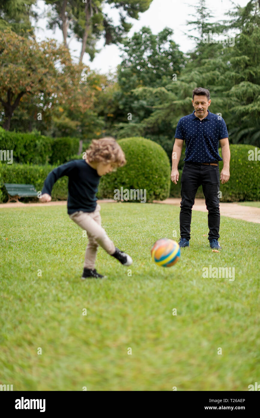 Father and son playing football in park Stock Photo - Alamy