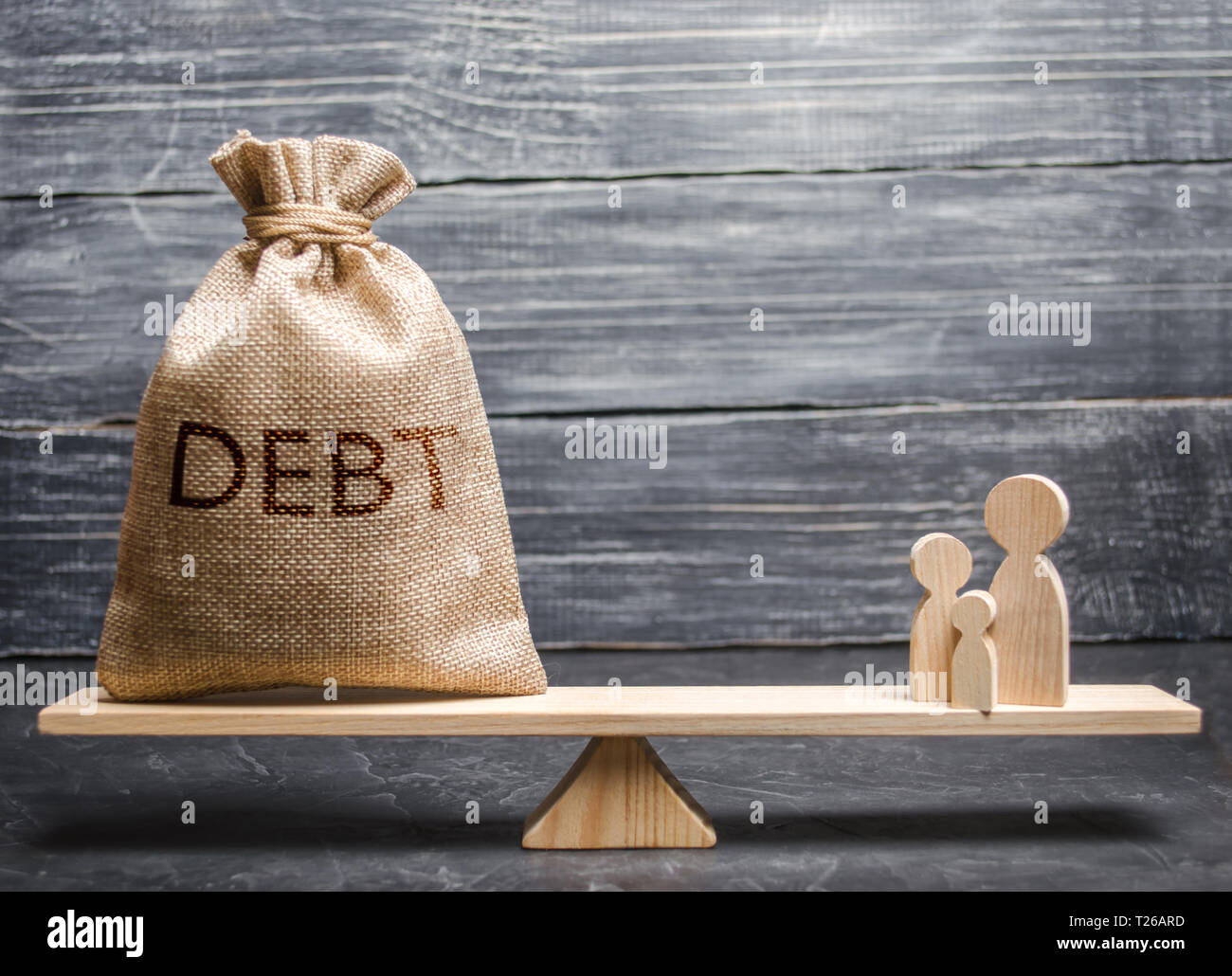 A bag with the inscription debt and family figures on the scales. The concept of loun burden on families. Financial illiteracy, debt pit and financial Stock Photo