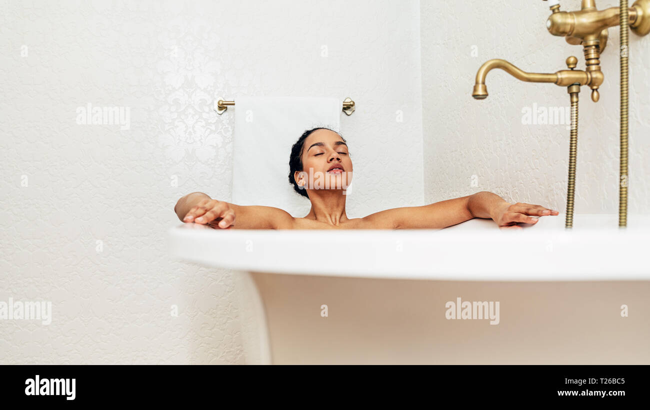 Young woman lying in bathtub with her eyes closed at home Stock Photo