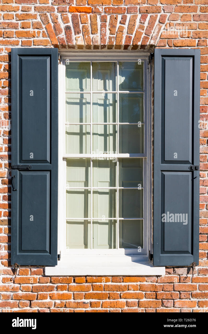 Exterior window of colonial brick home with black shutters Stock Photo
