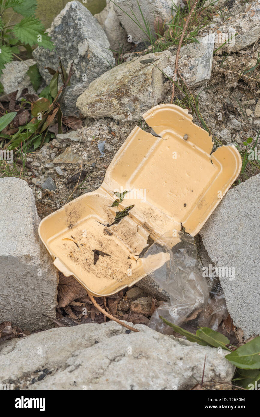 Generic foam takeaway food container on pile of builder#s / construction rubble. Street food rubbish, takeaway food packaging, single-use plastic ban. Stock Photo