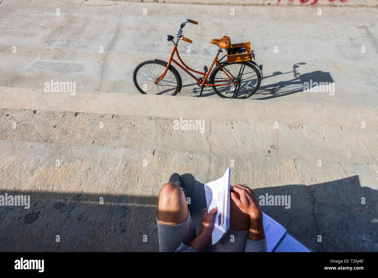 Young man with his scripts and parked bicycle in Valencia Port, Spain Stock Photo