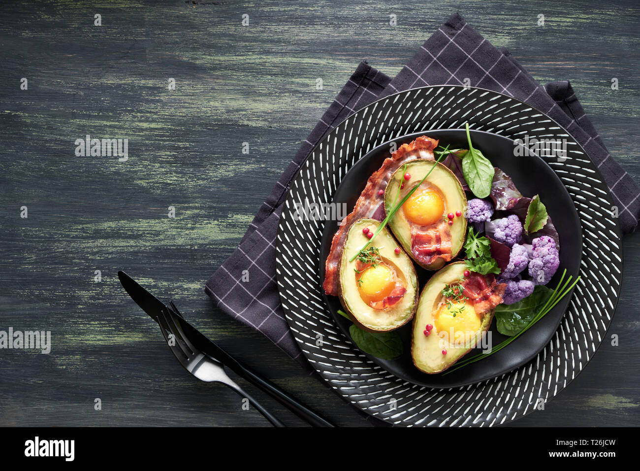 Baked avocado with egg and bacon ,flat lay on dark background Stock Photo