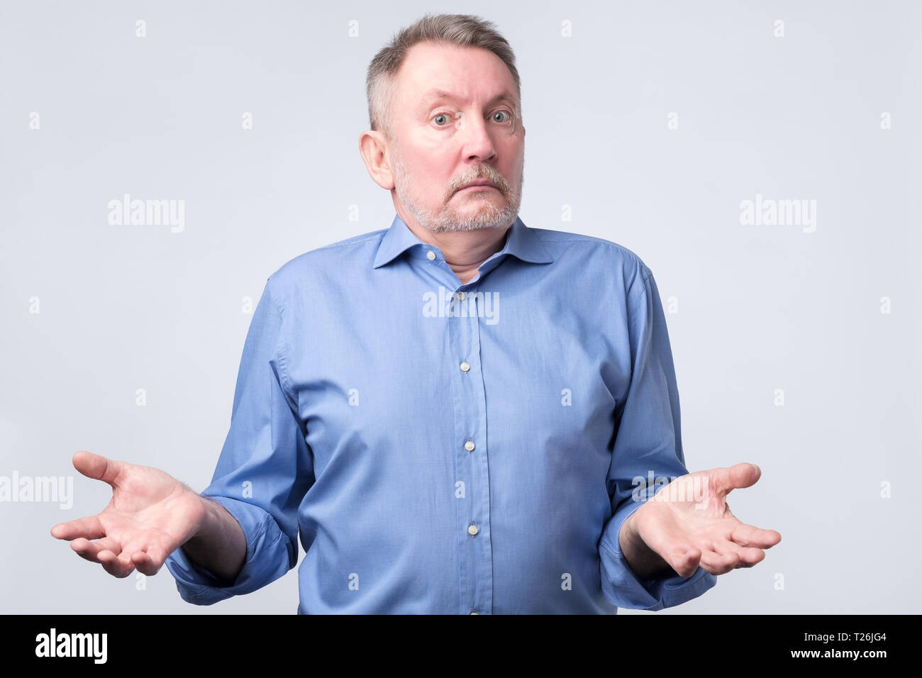 Confused senior caucasian man in blue shirt is unsure in studio. Studio shoot Stock Photo