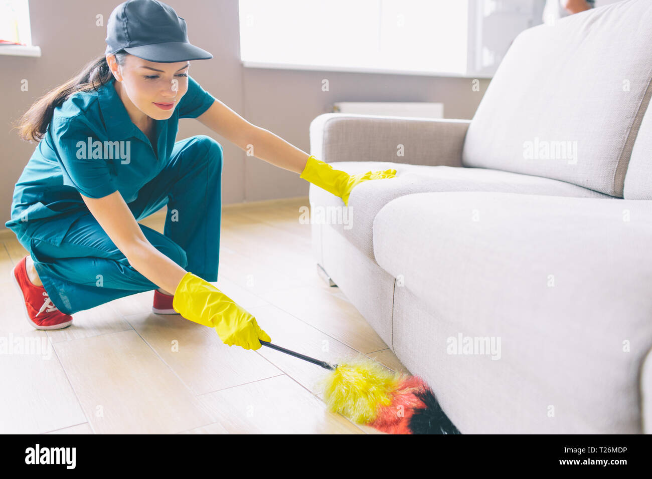 Cleaner is sitting in squad position and holding dust brush. She is