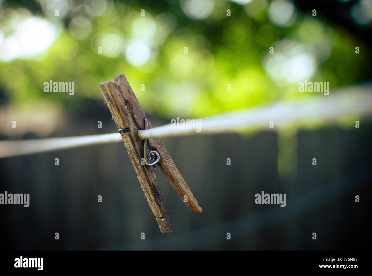 Wooden clothespin on vibrating line with soft green and brown background. Stock Photo