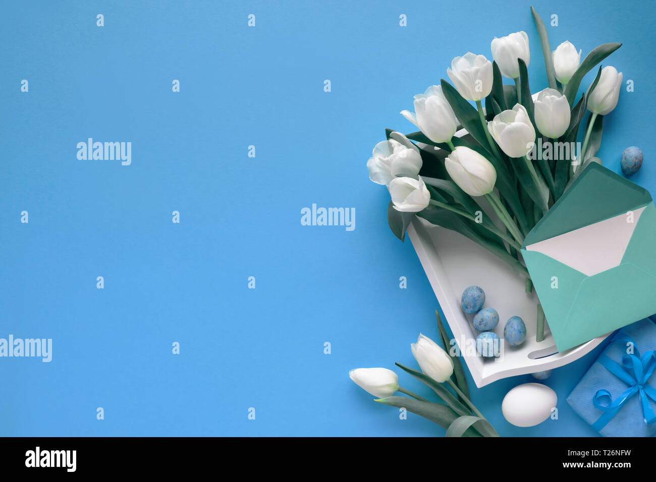 Easter border on blue paper background with copy-space. White tulips ...