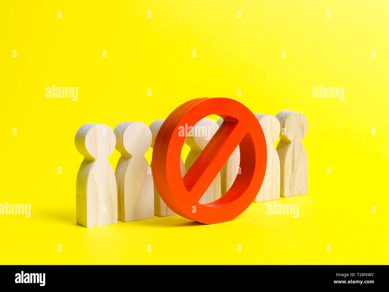 People figurines stand behind the red NO symbol on a yellow background. The concept of a ban on the expression of other opinions, suppression of disse Stock Photo