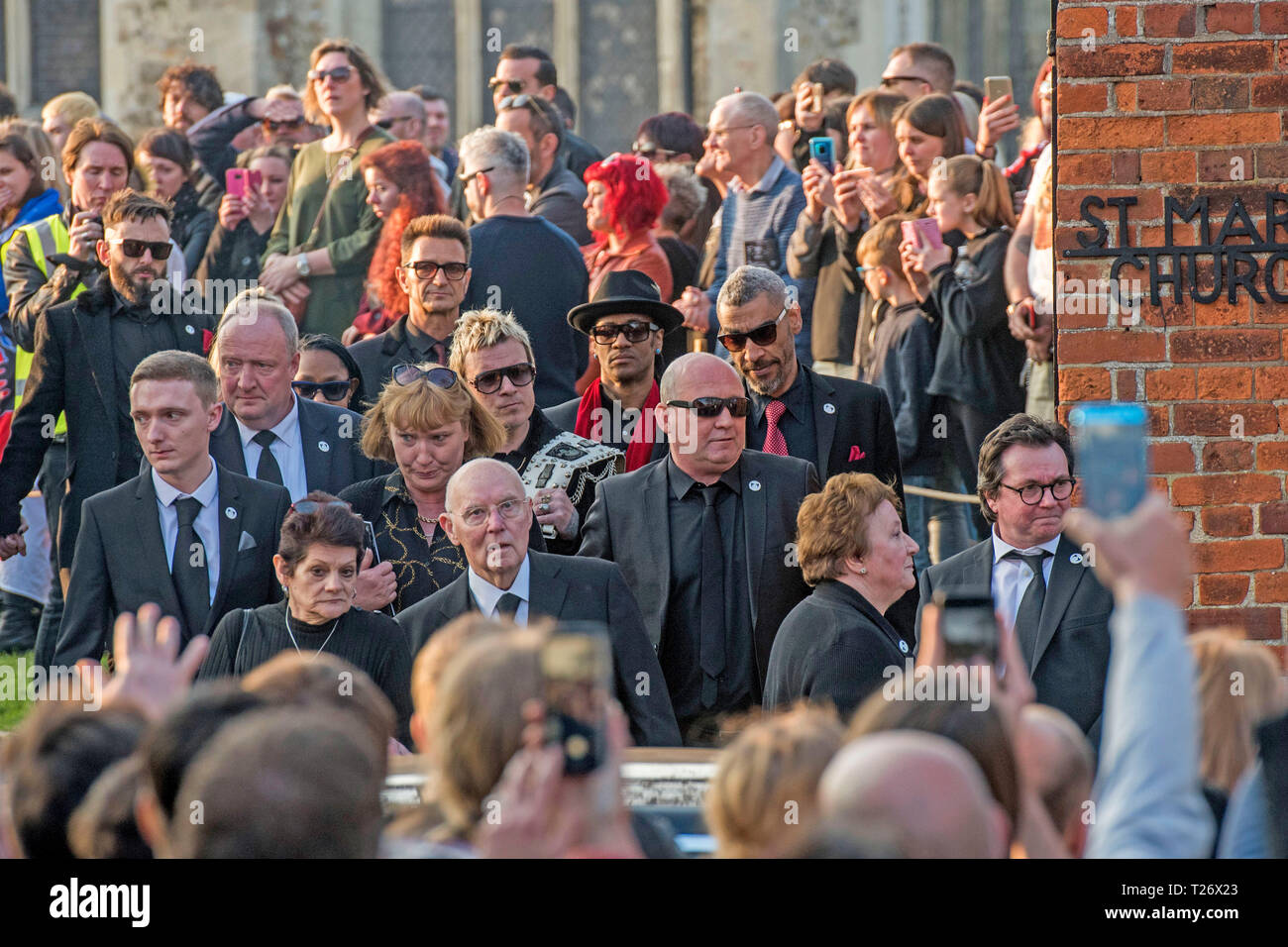Essex, UK. 30th March 2019. The  funeral of Prodigy singer Keith Flint at St Marys Church in Bocking,  Essex today. Mourners leave the service and band members Liam Howlett, Maxim (Keith Palmer) and Leeroy Thornhill can be seen following Keith’s father Clive Flint out of the front gates of the church. Credit: Phil Rees/Alamy Live News Stock Photo