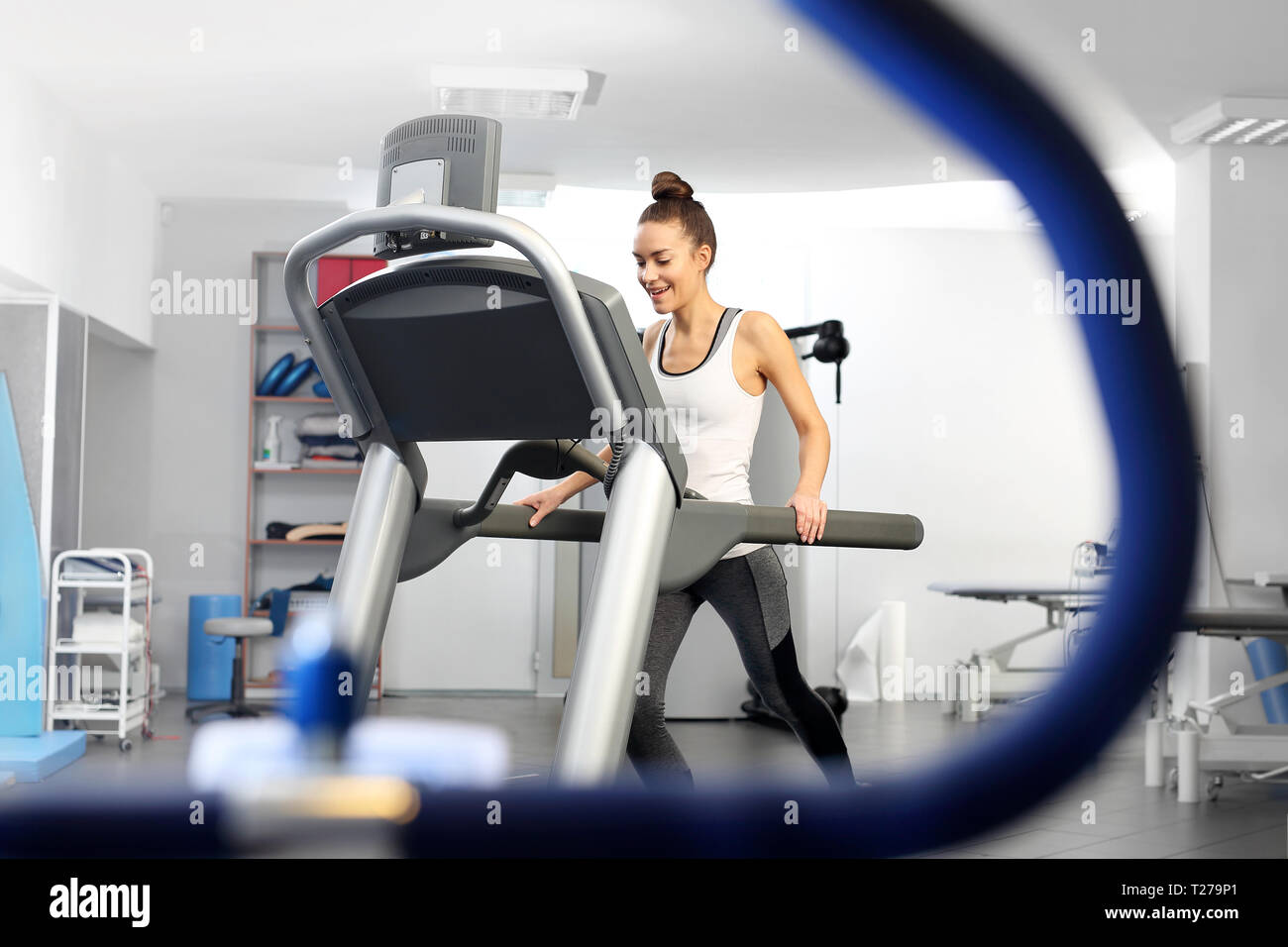A young woman in an exercise room is running on an automatic treadmill. Stock Photo