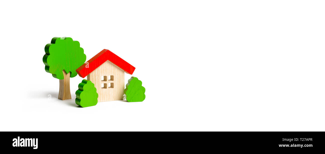 Wooden hut and tree figurines with bushes on an isolated background. The concept of a love nest. Acquisition of affordable housing in a mortgage or lo Stock Photo