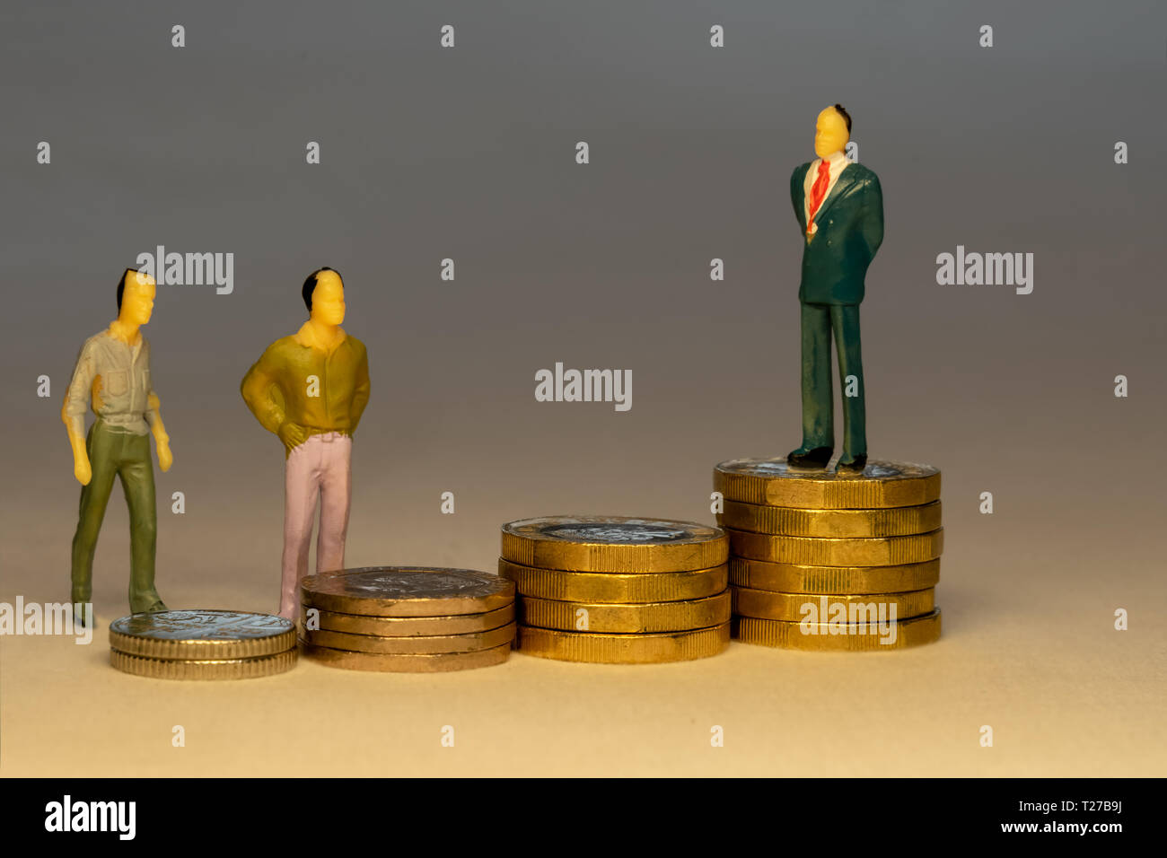 Ordinary people looking to business man standing on top of increasing piles of gold coins. Business career concept. Stock Photo