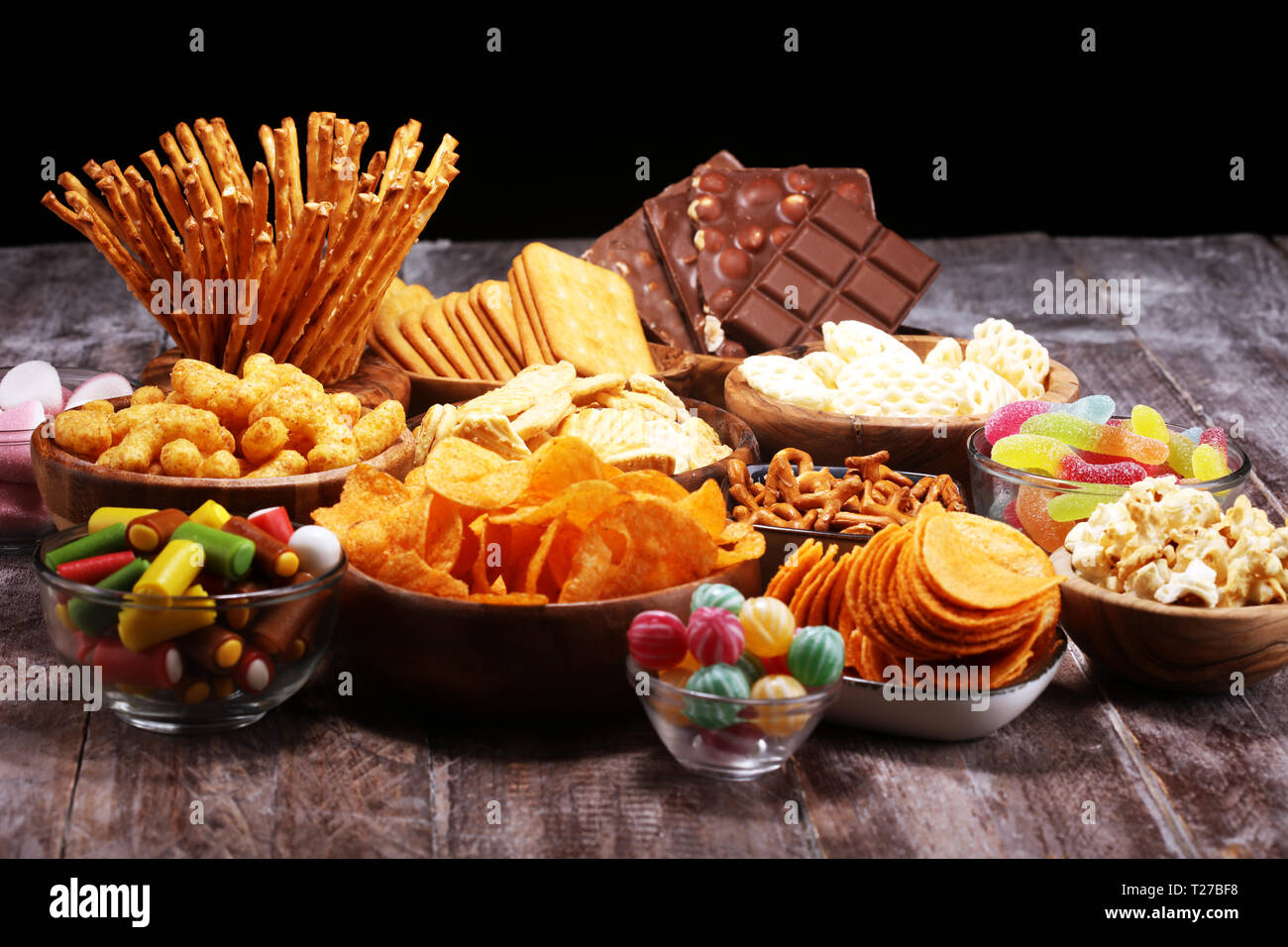 Salty snacks. Pretzels, chips, crackers in wooden bowls. Unhealthy