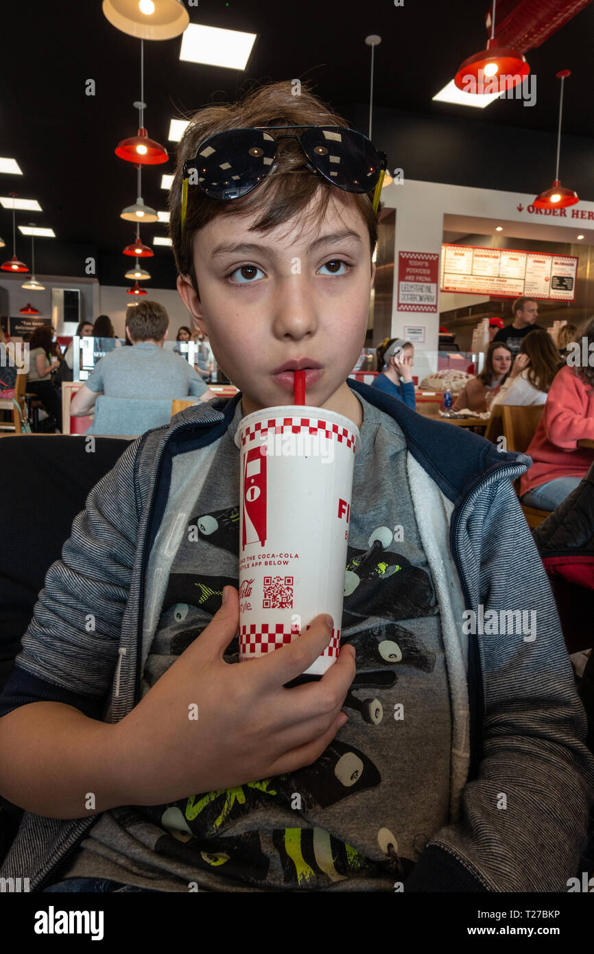A boys drinks a soft drink from a disposable paper cup in a Five Guys Fast  Food restaurant Stock Photo - Alamy