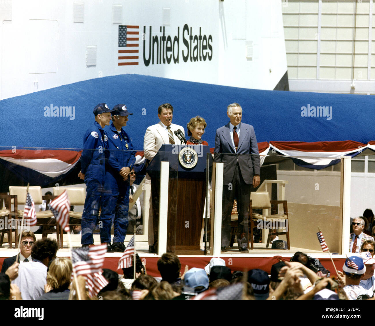 President Ronald Reagan speaks to a crowd of more than 45,000 people at NASA's Dryden Flight Research Center following the landing of STS-4 on July 4, 1982. To the right of the President are Mrs. Reagan and NASA Administrator James M. Beggs. To the left are STS-4 Columbia astronauts Thomas K. Mattingly and Henry W. Hartsfield, Jr. Prototype Space Shuttle Enterprise is in the background. Stock Photo