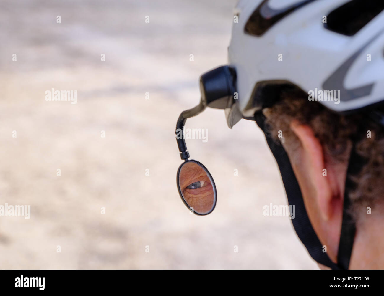 View of a senior bicyclist's eye reflected in side mirror attached to helmet Stock Photo