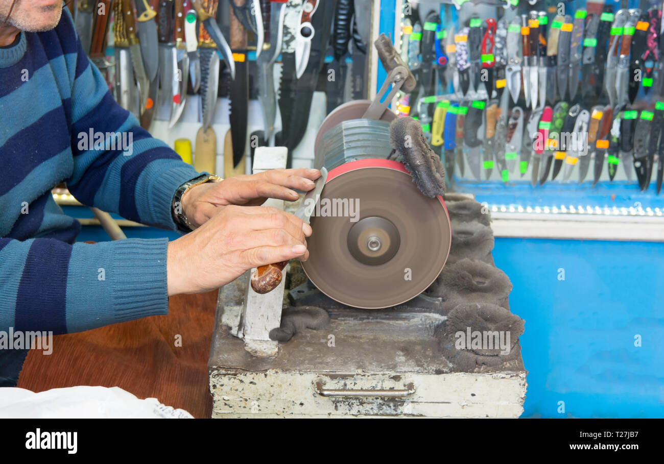 knife sharpening machine and master. Grinding machine. grinding knife using abrasive stone Stock Photo