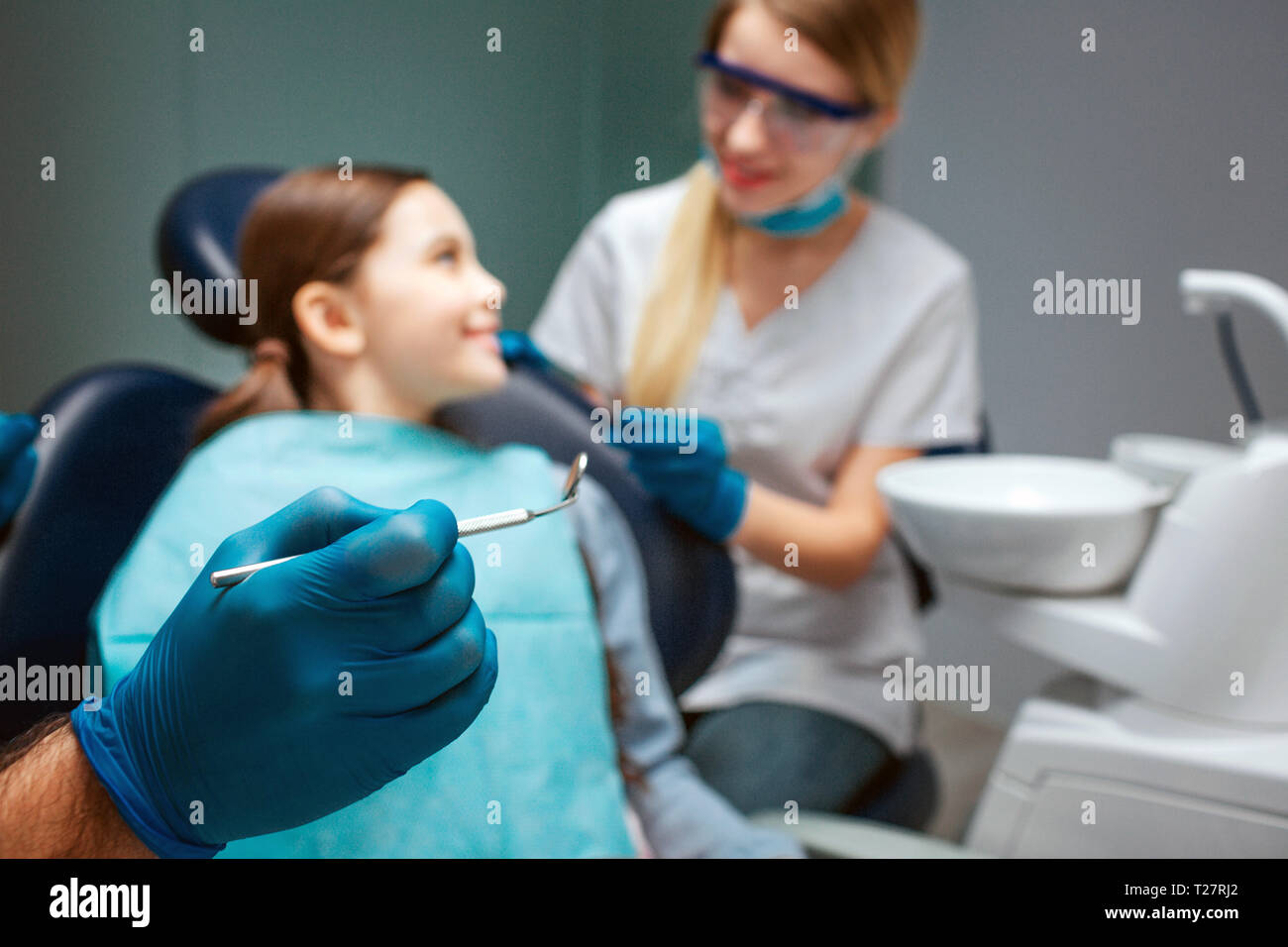 Hand in latex glove hold dental tool hold dental tool. Child sit in