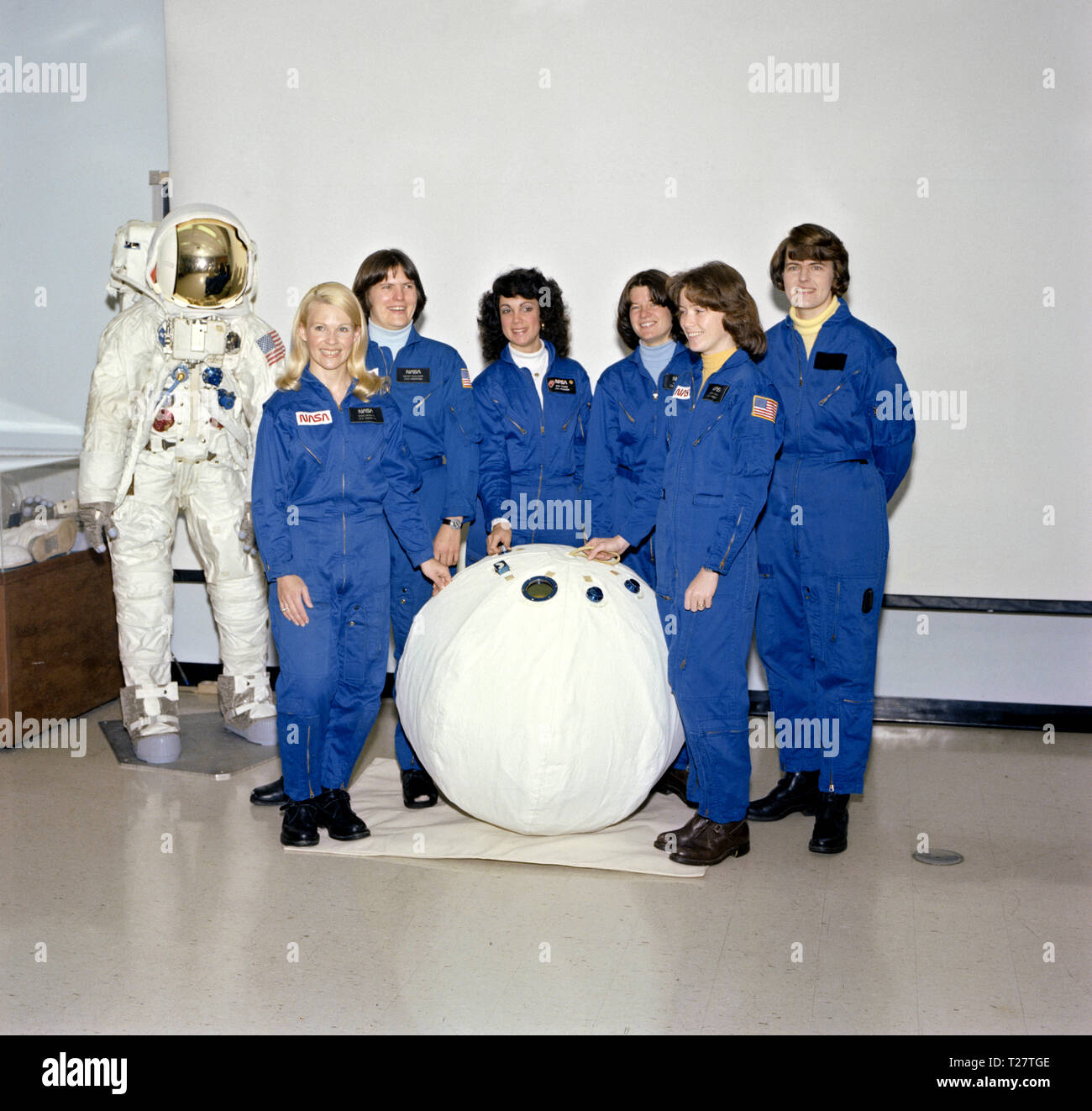 (28 Feb 1979) --- Sporting their new Shuttle-type constant-wear garments, these six astronaut candidates pose for a picture in the crew systems laboratory at the Johnson Space Center (JSC) with the personnel rescue enclosure (PRE) or 'rescue ball' and an unoccupied Apollo EMU.  From left to right are Rhea Seddon, Kathryn D. Sullivan,  Judith A. Resnik,  Sally K. Ride, Anna L. Fisher and Shannon W. Lucid. Stock Photo
