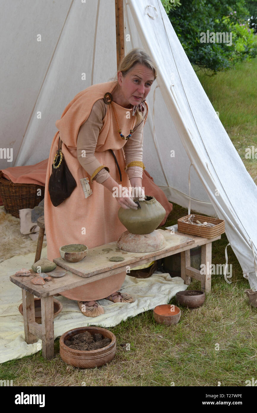 Anglo-Saxon lady re-enactor working with clay pottery at an event in Suffolk, UK Stock Photo