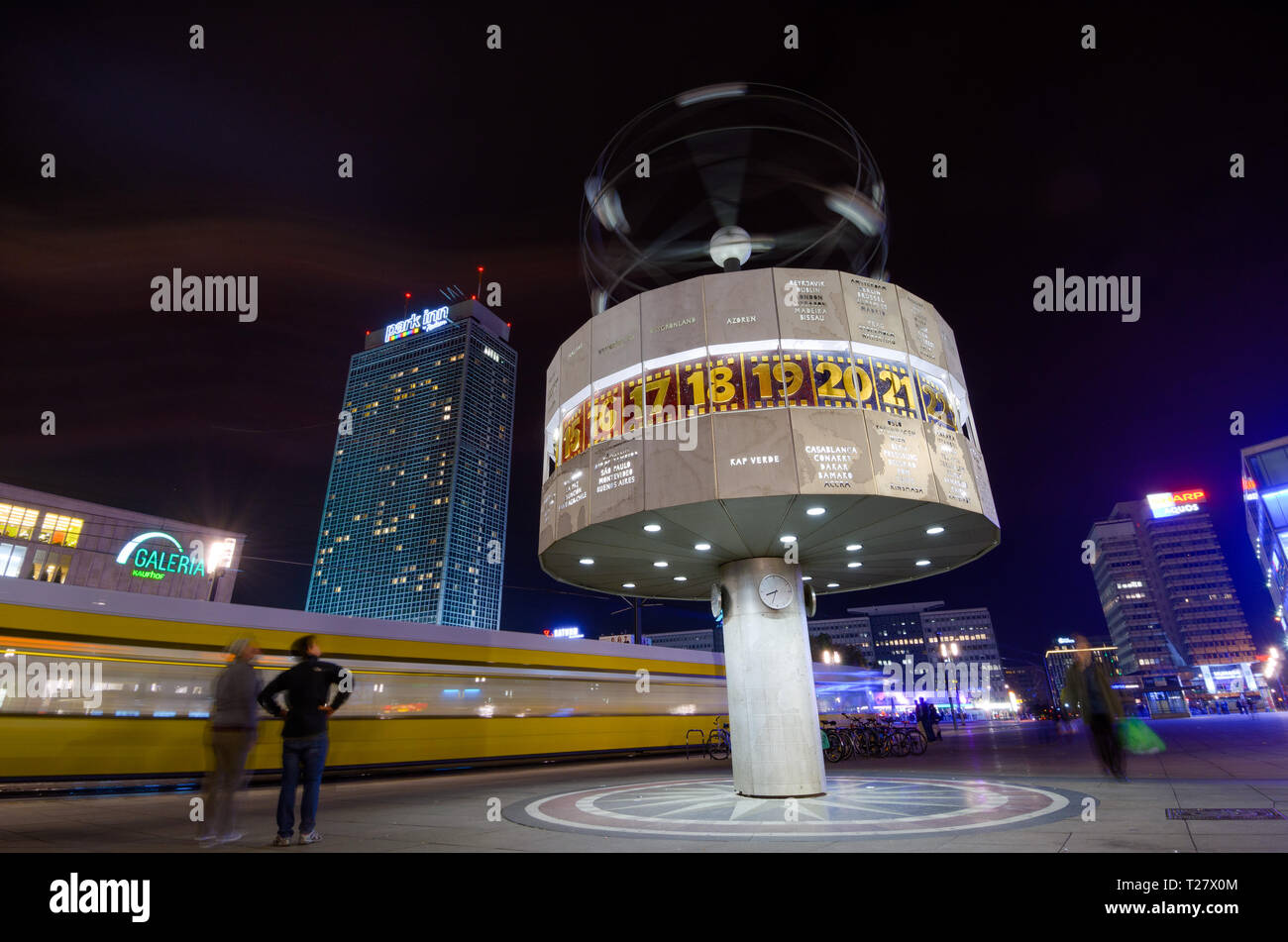 BERLIN, GERMANY - 9 Nov 2012: Weltzeituhr, the worldtime clock at night, with a tram passing and bystanders, in Alexanderplatz, Berlin, Germany. Stock Photo