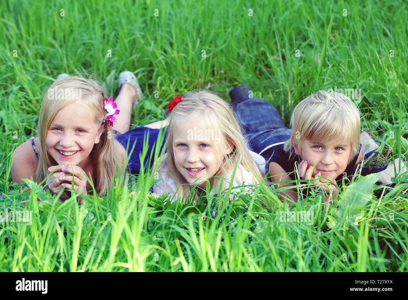 Friendly kids lying on green grass in summer park Stock Photo Alamy