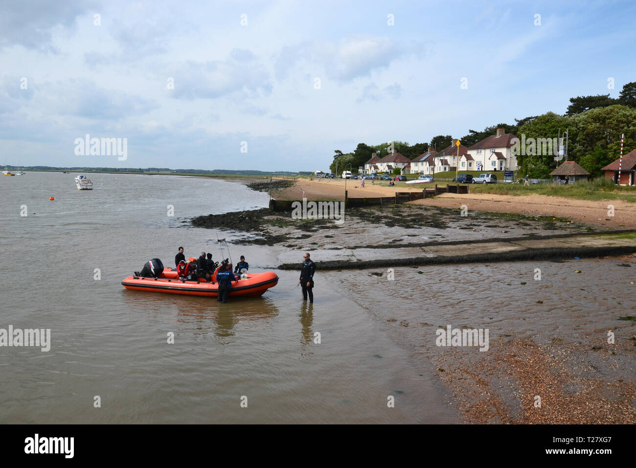 A boat full of people arriving on the beach at Bawdsey, Suffolk, England, UK Stock Photo