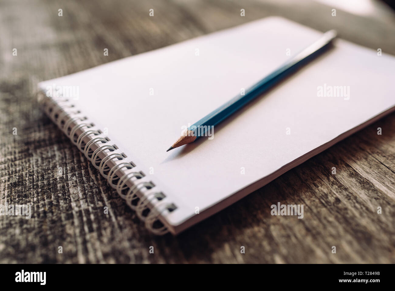 A pencil and a notebook on wooden surface close up. Stock Photo