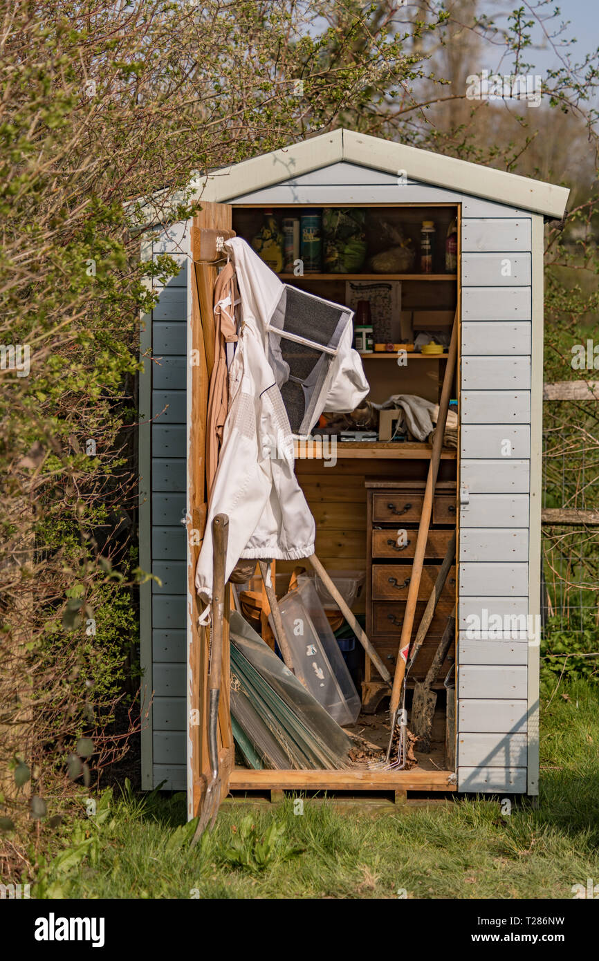 Garden shed with bee suit and garden tools hires stock photography and