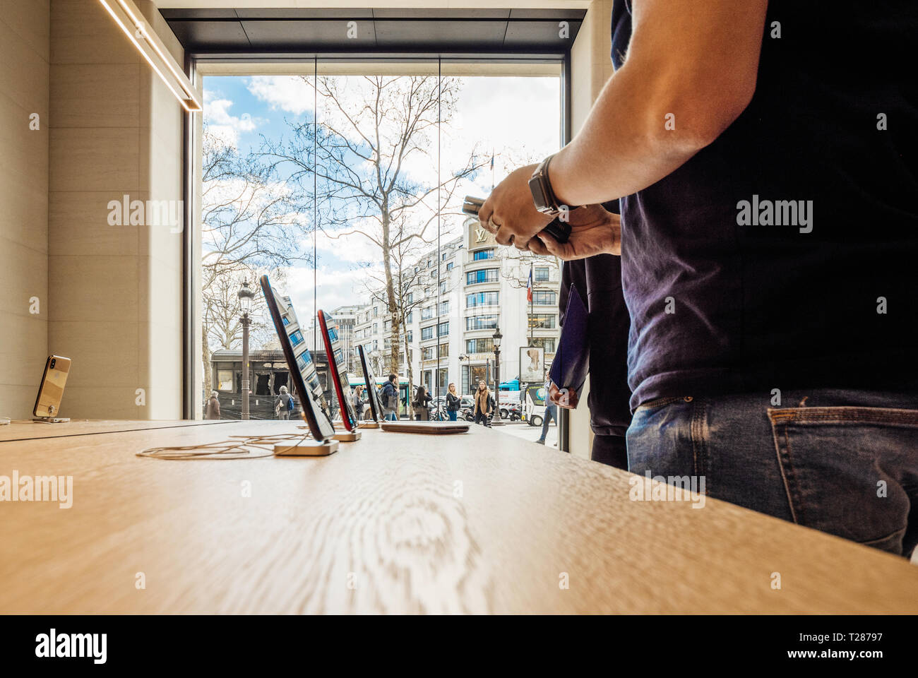 Paris, France - Circa 2019: Apple iPhone XS smartphones products are displayed inside the new Apple Store Champs-Elysees with Genius worker selling iPhone  Stock Photo