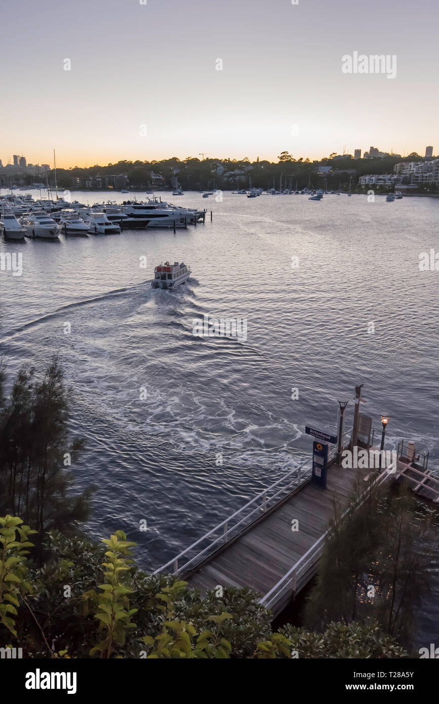 An early morning water taxi leaves Birkenhead point wharf below the Iron Cove Bridge in the upper reaches of Sydney harbour. Stock Photo