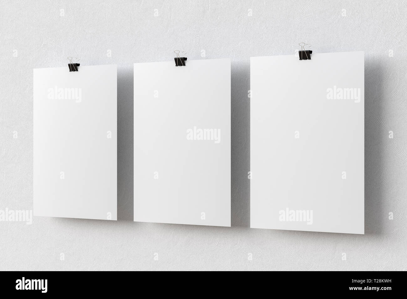 Three blank paper posters hanging on binder clips on white wall