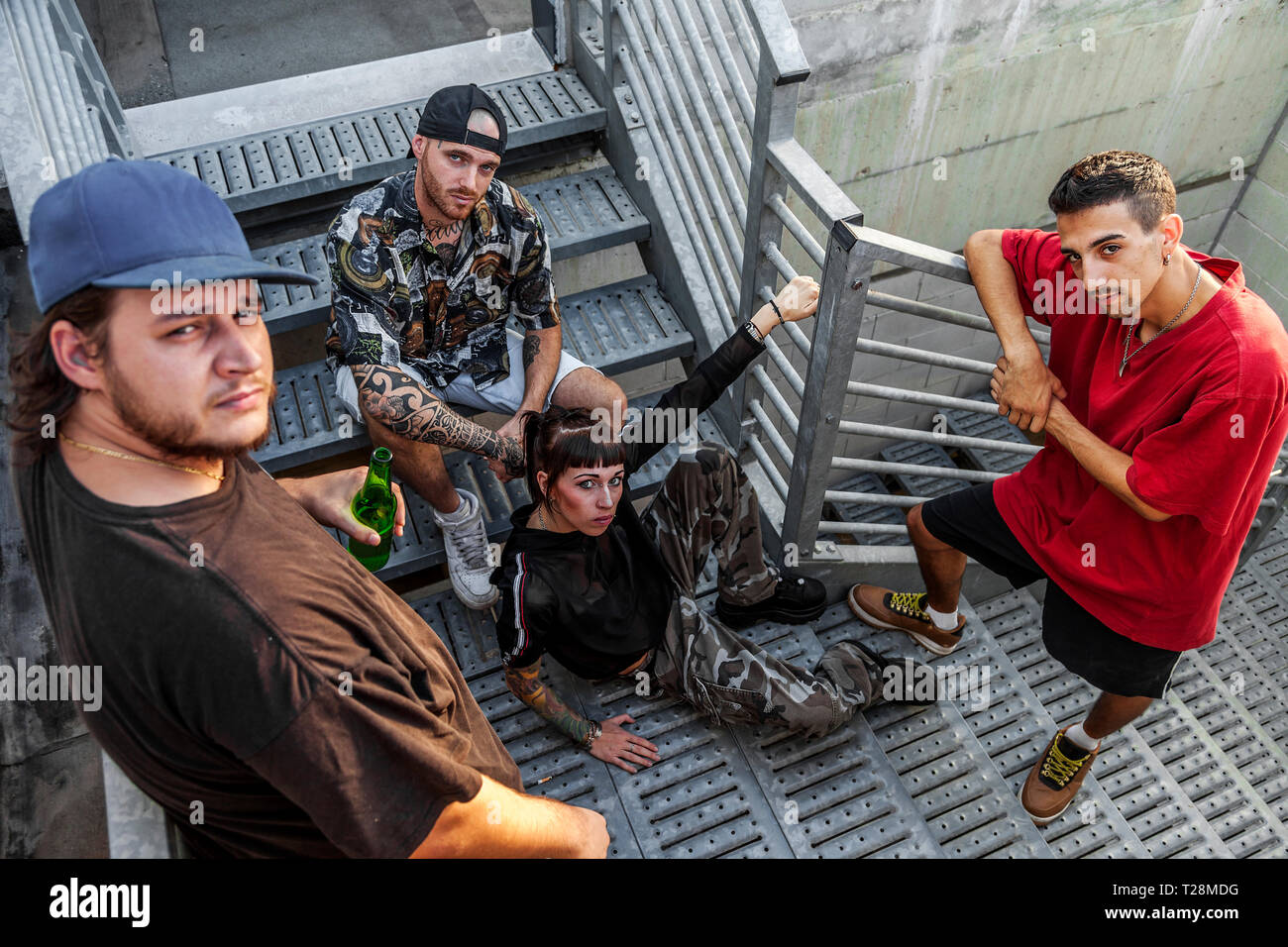 group of young rappers posing on the metal stairs of an abandoned ...