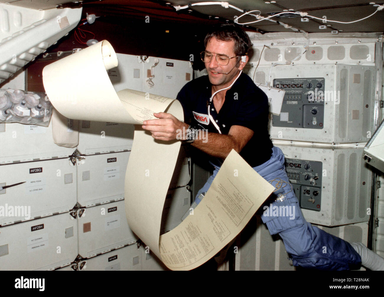 (12-14 Nov. 1981) --- Astronaut Richard H. Truly, STS-2 pilot, peruses some teleprinter copy, floating partially about the middeck area of NASA’s space shuttle Columbia during one of 1,813 minutes of activity of STS-2. This photograph was recorded with 35mm camera in the hands of astronaut Joe H. Engle, STS-2 crew commander. Truly communicates with spacecraft communicators on the ground. Photo credit: NASA Stock Photo