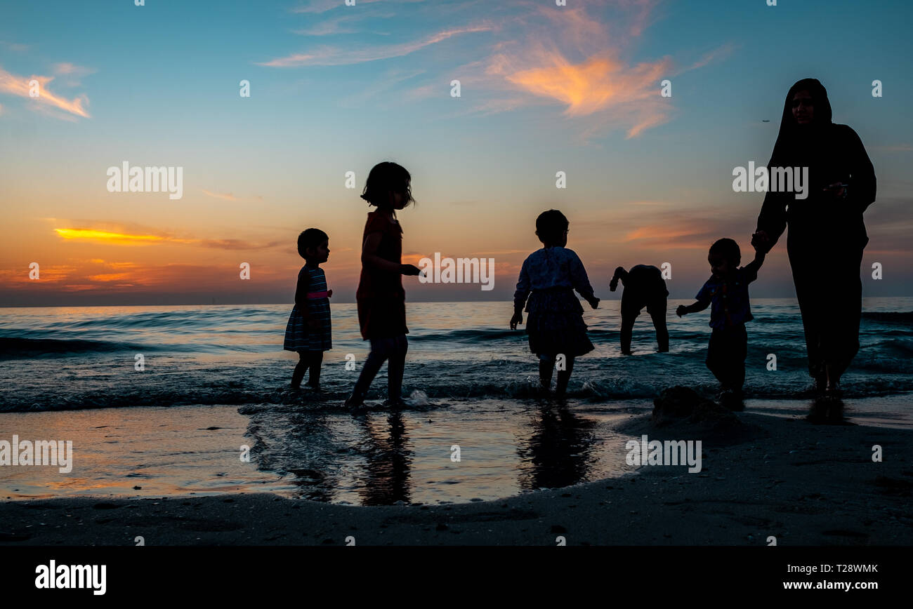 Kids collecting sea shells during sunset at beach Stock Photo Alamy