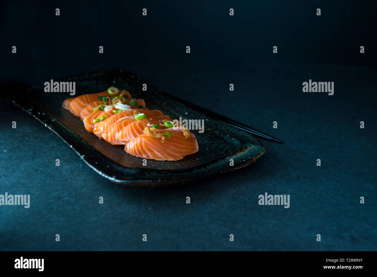 Sliced salmon sashimi on plate with dark background and copy space, low key image Stock Photo
